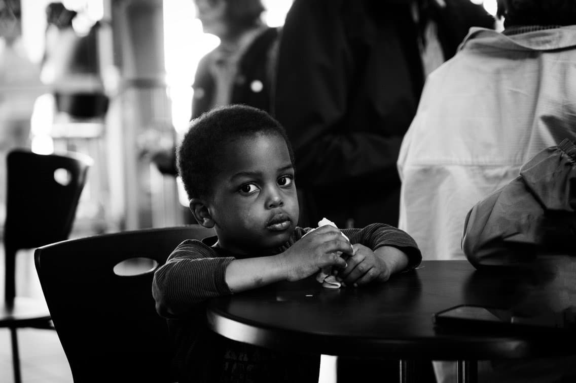 enfant pensif assis à une table ronde dans un café ou un restaurant